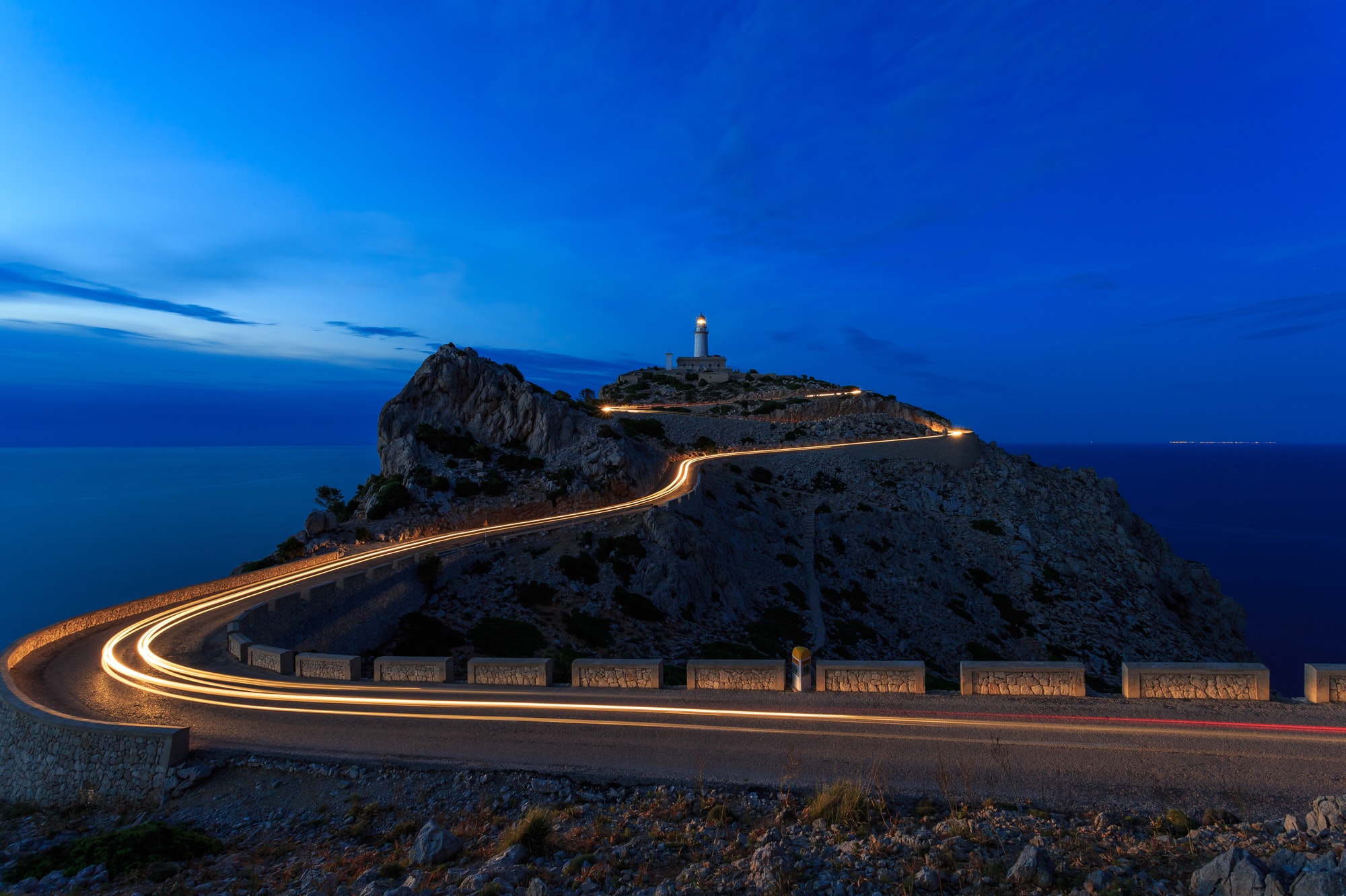 long exposure road at night with a light house in hill