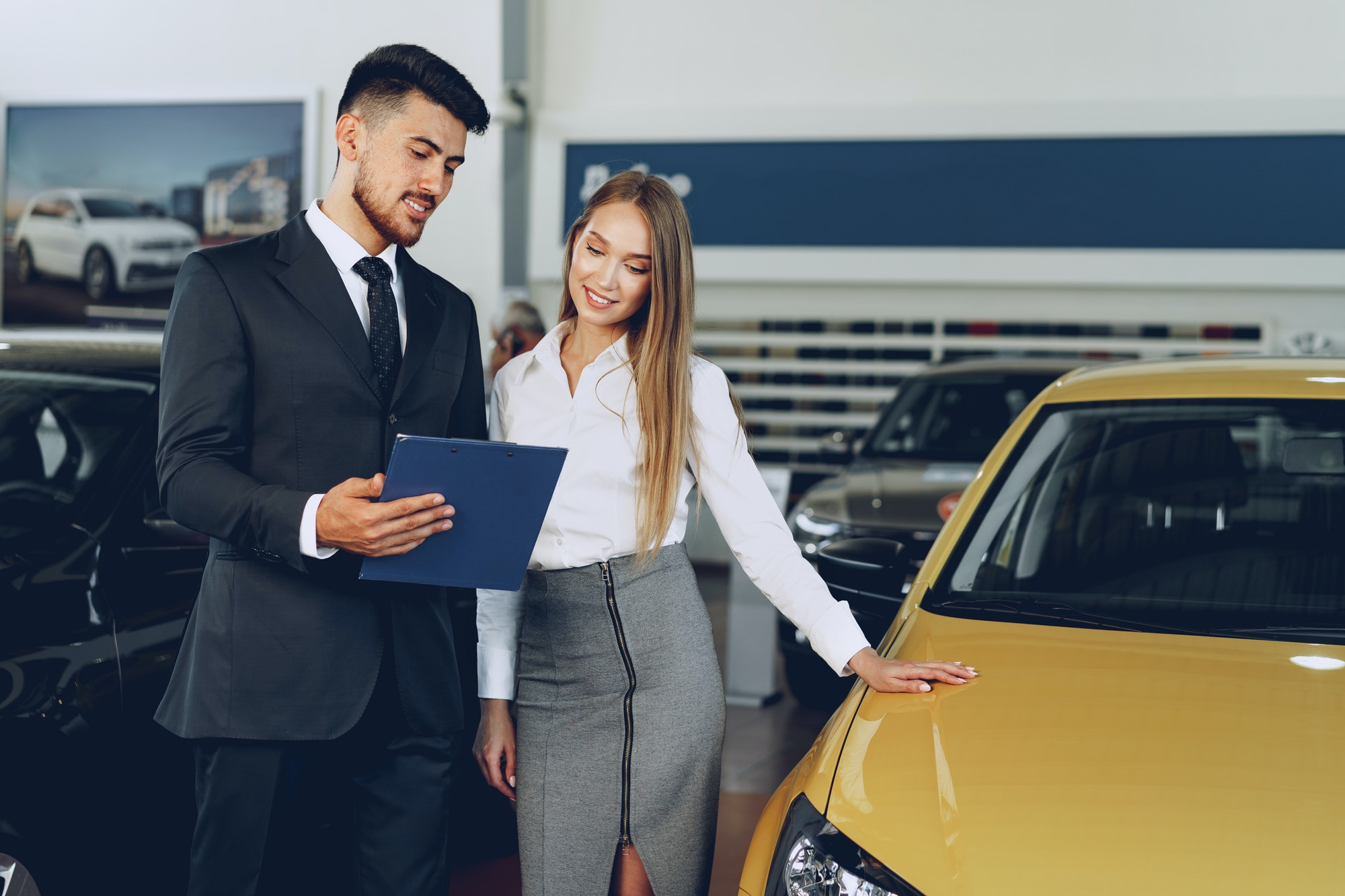 Man car dealer showing a woman buyer a new car